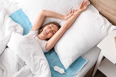 mujer tumbada en la cama con la manta el&eacute;ctrica
