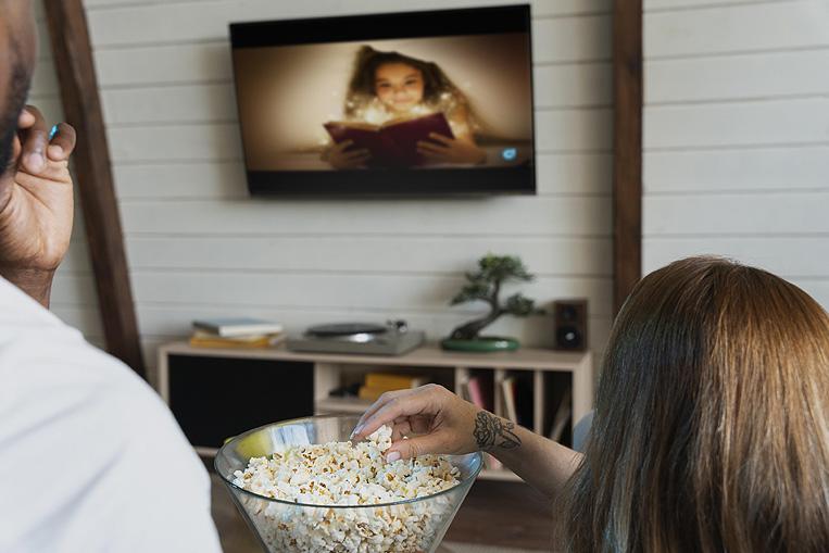 Pareja viendo la televisi&oacute;n comiendo palomitas
