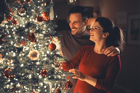 Pareja poniendo las luces del &aacute;rbol de Navidad
