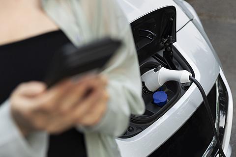 mujer cargando la bater&iacute;a de su coche el&eacute;ctrico