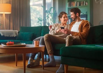 pareja sentada en el sof&aacute; mirando el m&oacute;vil
