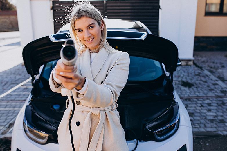 mujer con cable del cargador de coche el&eacute;ctrico